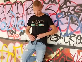 Young guy masturbates in public in front of graffiti wall